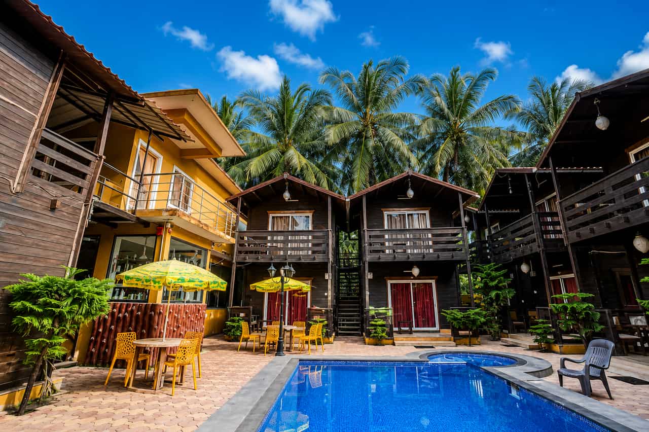 Timber cottage rows around the pool at WENZET Cottages, Goa
